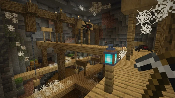 Spooky Minecraft abandoned mineshaft scene with wooden structures, lanterns, and spider webs inside a cave.